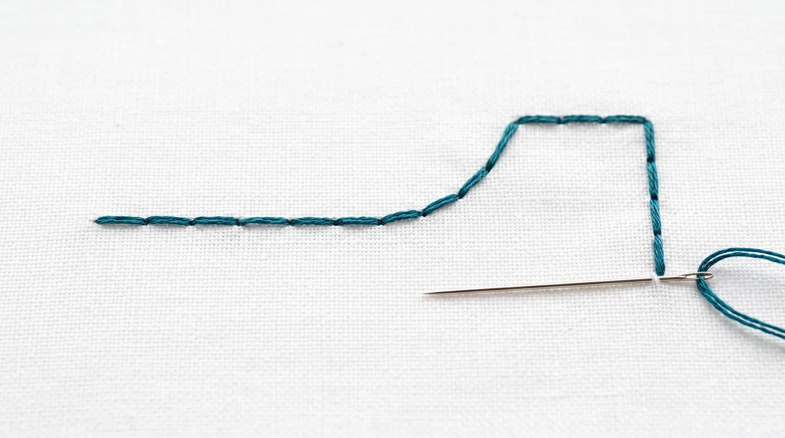 Connected teal backstitch segments forming a straight line, curved rise and square corner on white fabric