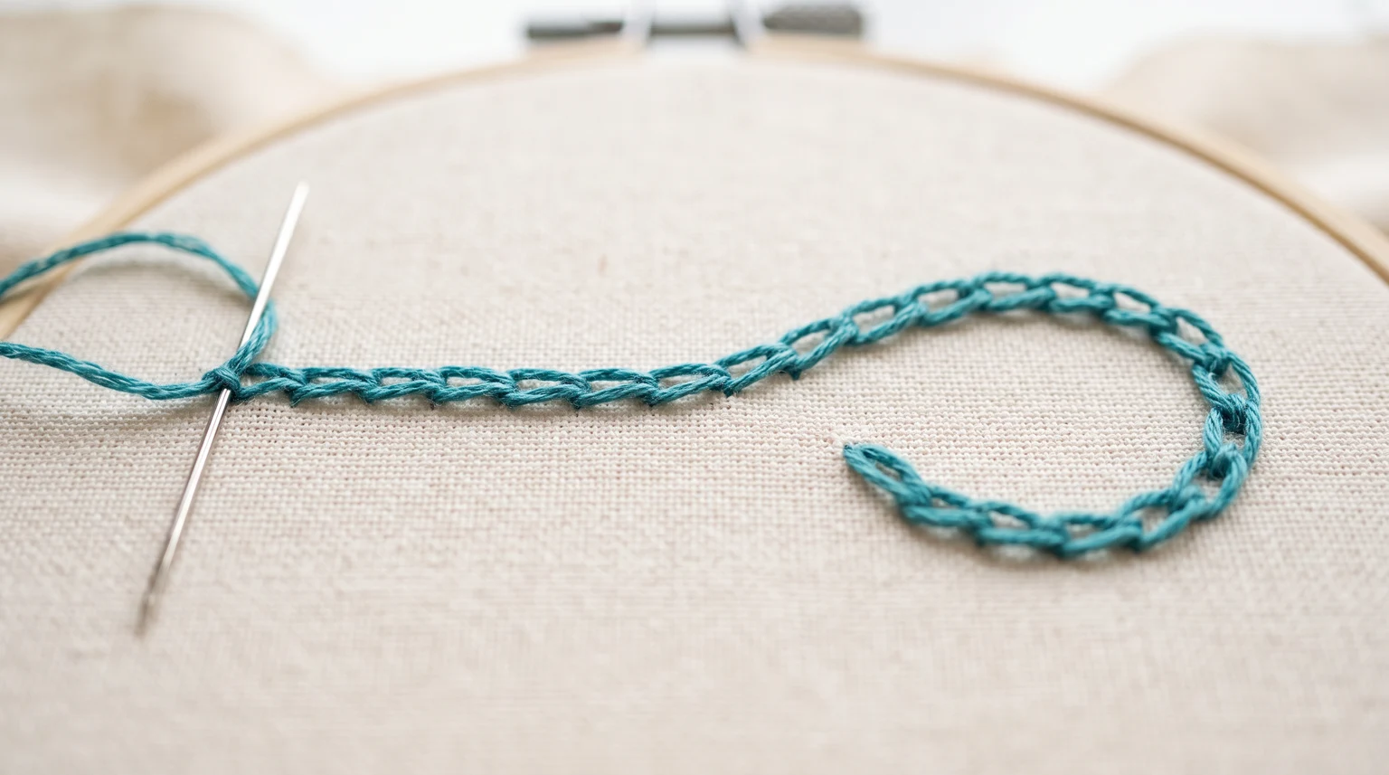 Teal open linked chain loops following a curved line on fabric