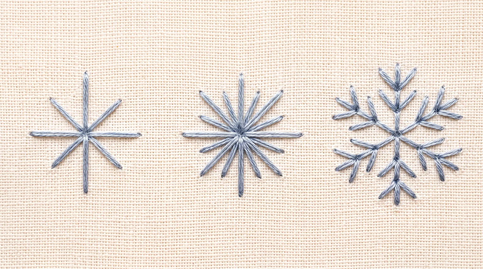 Three silver-blue stitched motifs showing a simple sparkle, a fuller starburst and a branched snowflake