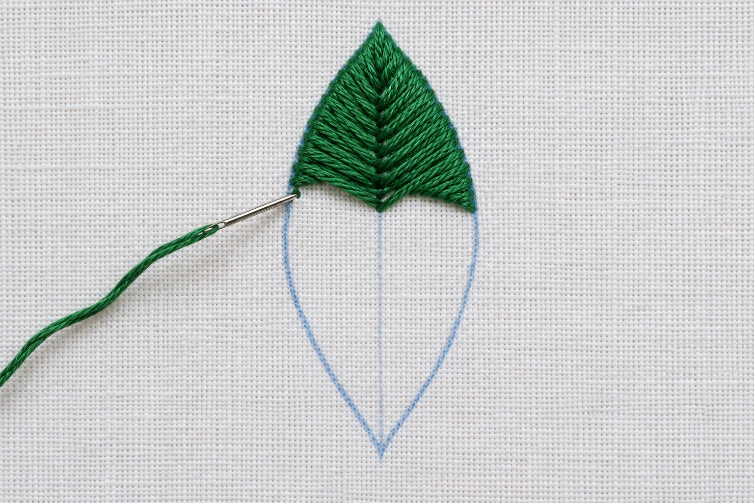 Partly filled green fishbone leaf with a blue outline, center guideline and needle at the left edge