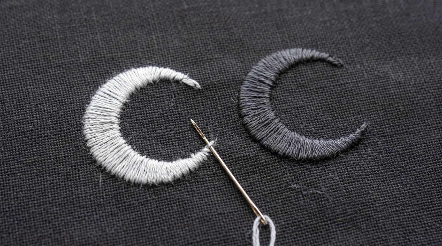 Pale and charcoal stitched crescents on the same dark fabric