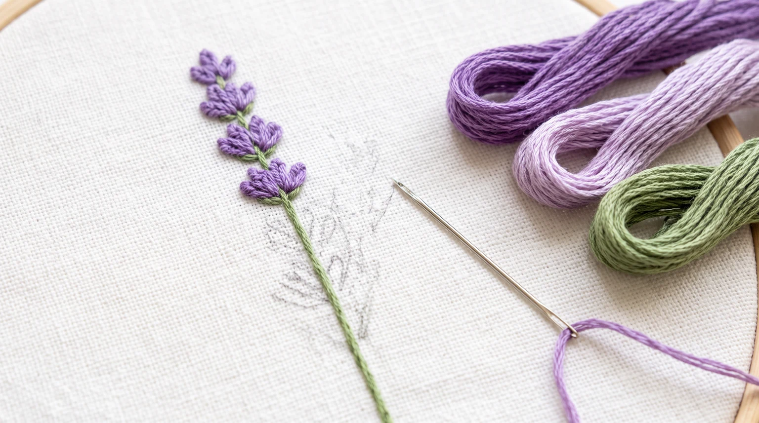 Small lavender sprig beside two purple floss shades, green thread and a working needle