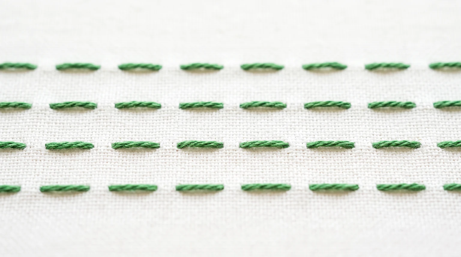 Three rows of short green running stitches with visible fabric gaps between the dashes