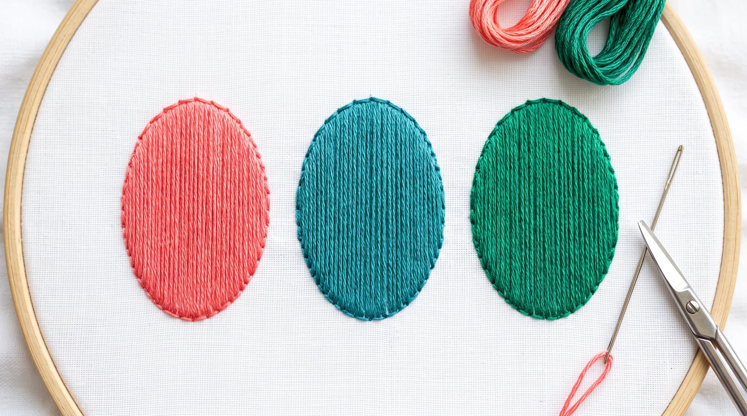 Coral, teal and green oval shapes filled with straight parallel vertical satin stitches