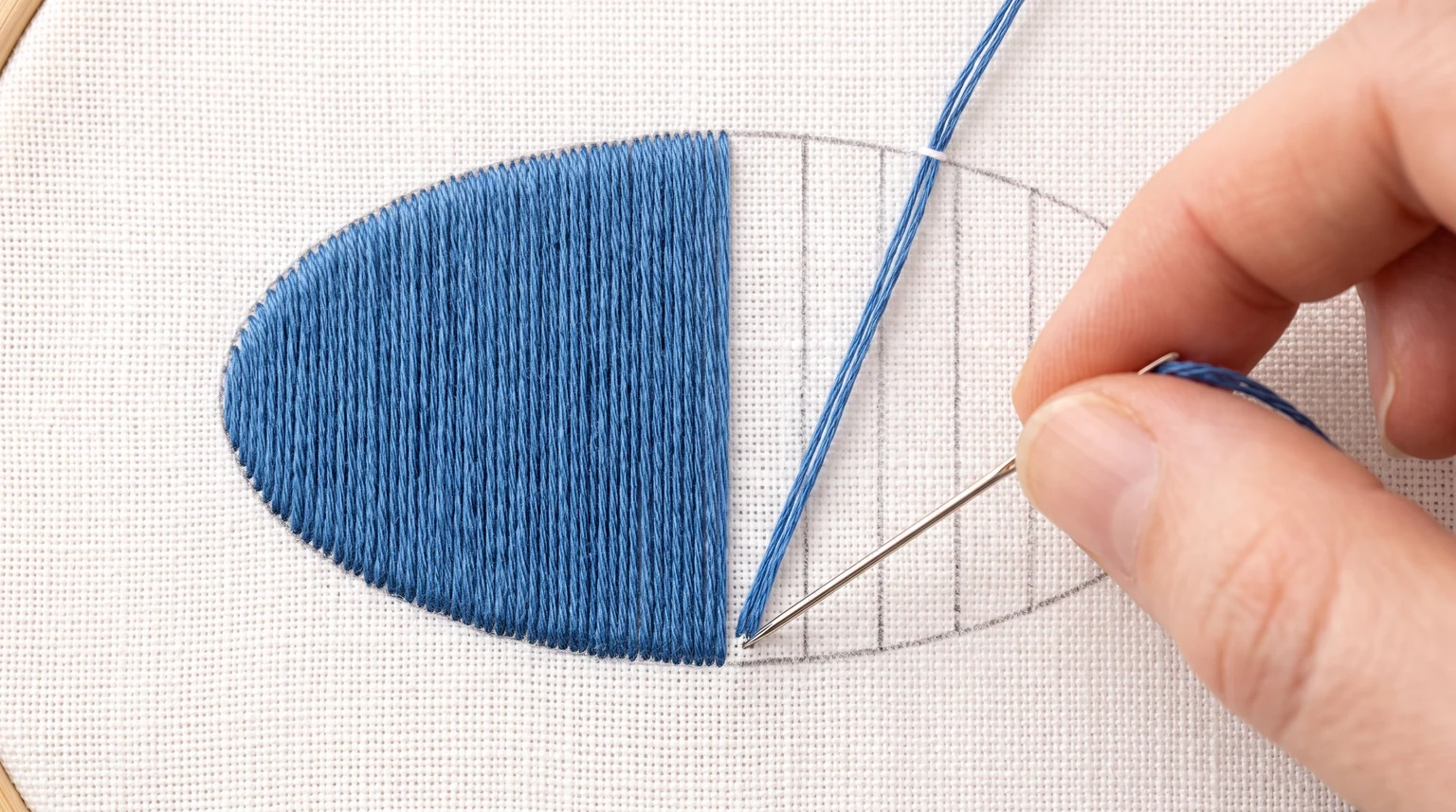 Partly filled blue oval with vertical satin stitches and matching vertical direction marks in its unfilled area