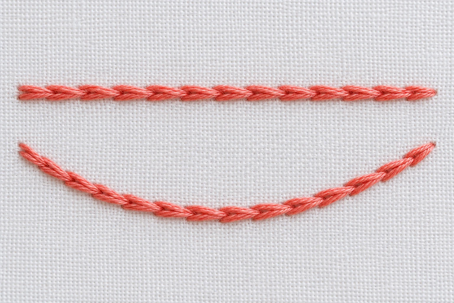 Coral embroidery samples showing a compact straight line and a gently curved line on white cotton