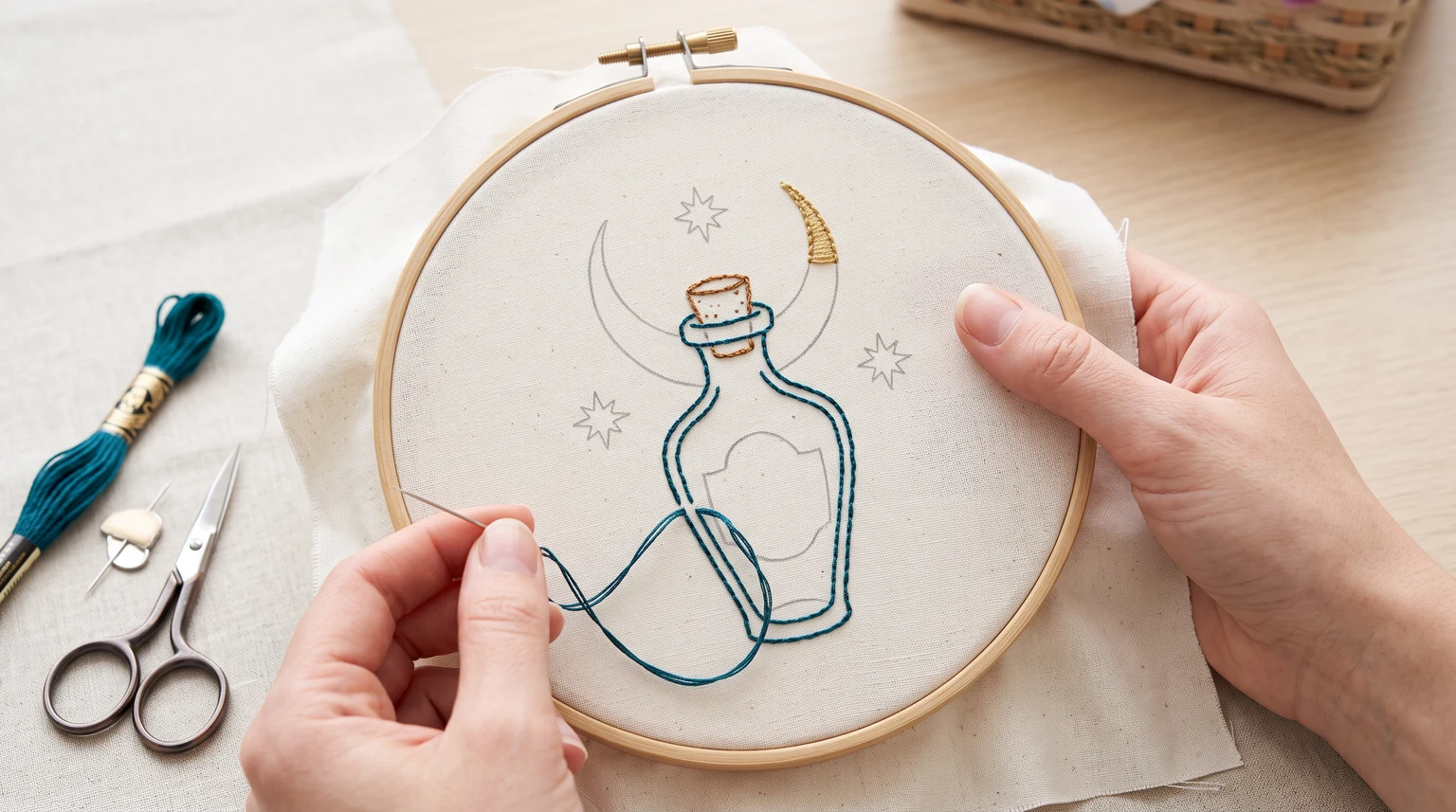 Partly stitched blue bottle motif with crescent and small stars in a hoop